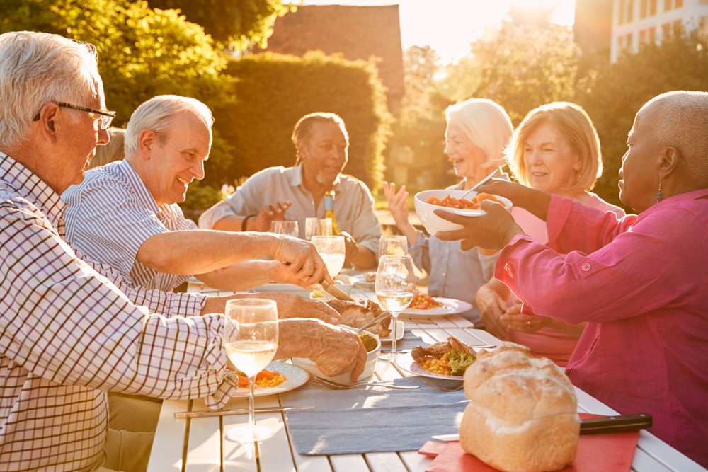 Group of senior friends sitting down and eating together