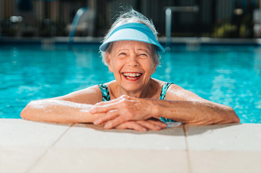 A senior woman floats by the edge of a swimming pool