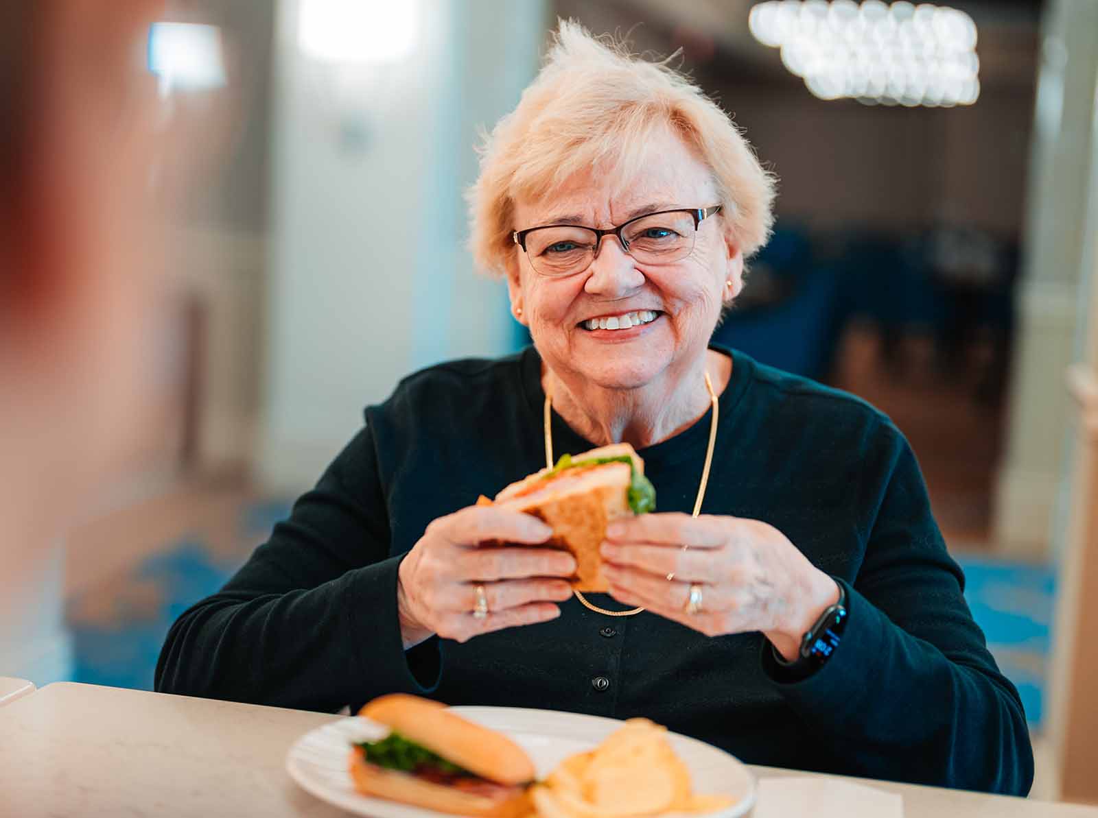 A senior woman enjoys a sandwich