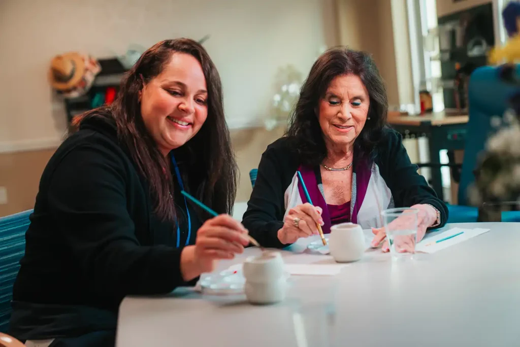 Two women glazing small pottery in an art studio