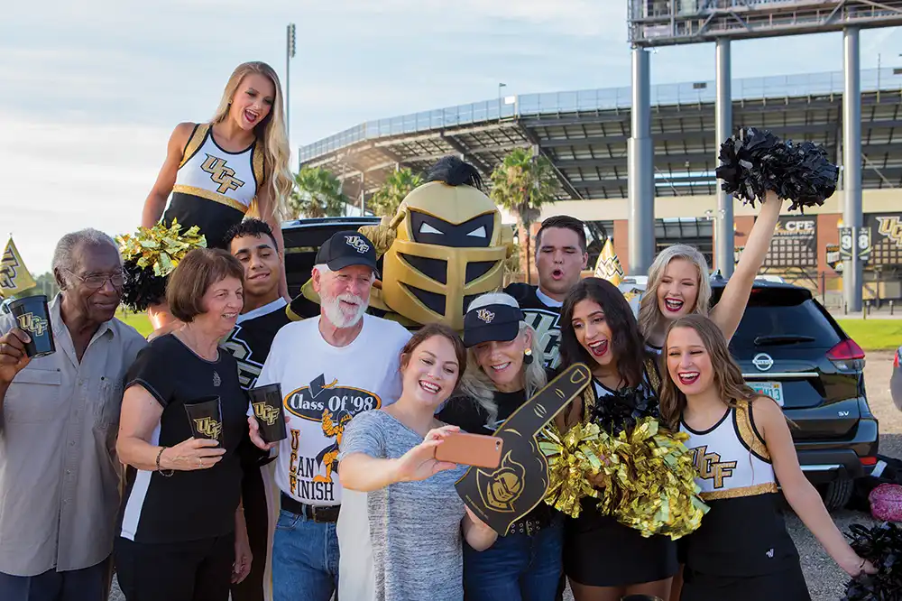 A group of University of Central Florida alumni gather around to take a selfie