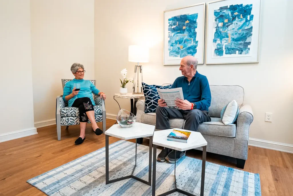 A senior couple are seated together in a living room, talking to each other